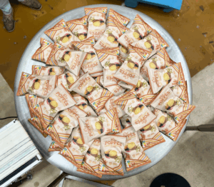 une multitude de paquets de chips saveur curry posé sur une table ronde en métal