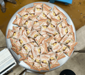 une multitude de paquets de chips saveur curry posé sur une table ronde en métal